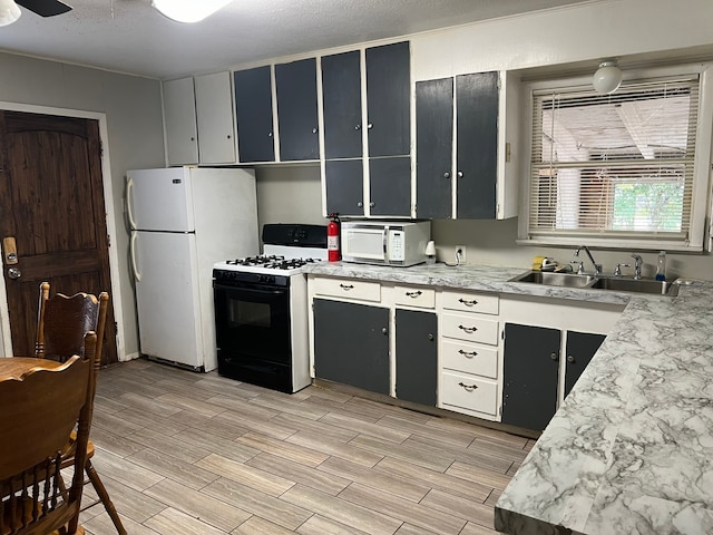 kitchen featuring ceiling fan, sink, white appliances, a textured ceiling, and light hardwood / wood-style flooring