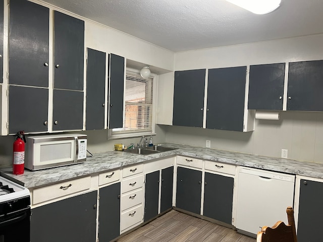 kitchen featuring dishwasher, light hardwood / wood-style flooring, sink, and a textured ceiling