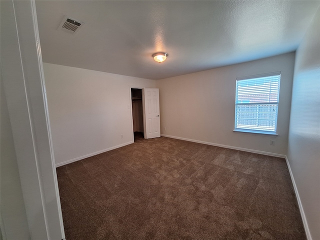 spare room featuring dark carpet