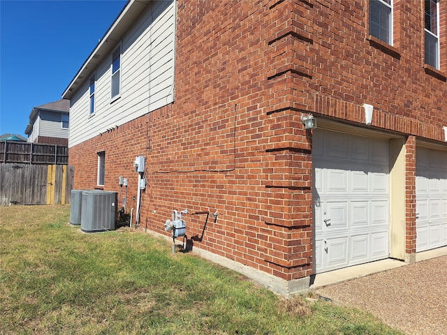 view of side of home with a lawn, a garage, and central air condition unit