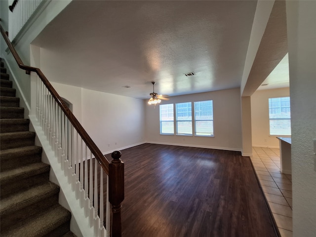 unfurnished living room with a textured ceiling, wood-type flooring, and ceiling fan