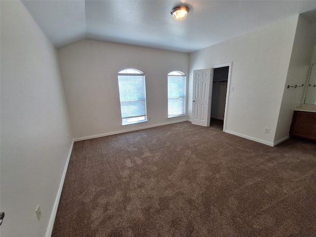 unfurnished bedroom with a closet, dark colored carpet, and vaulted ceiling