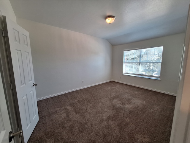 unfurnished room featuring lofted ceiling and dark colored carpet