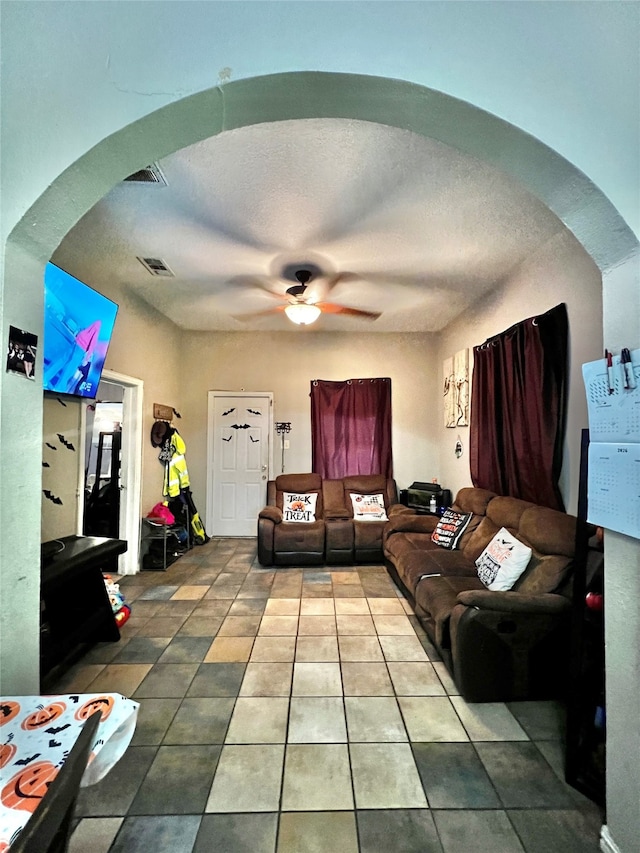 tiled living room with ceiling fan and a textured ceiling