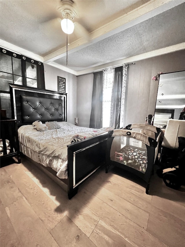 bedroom with a textured ceiling, wood-type flooring, and ceiling fan