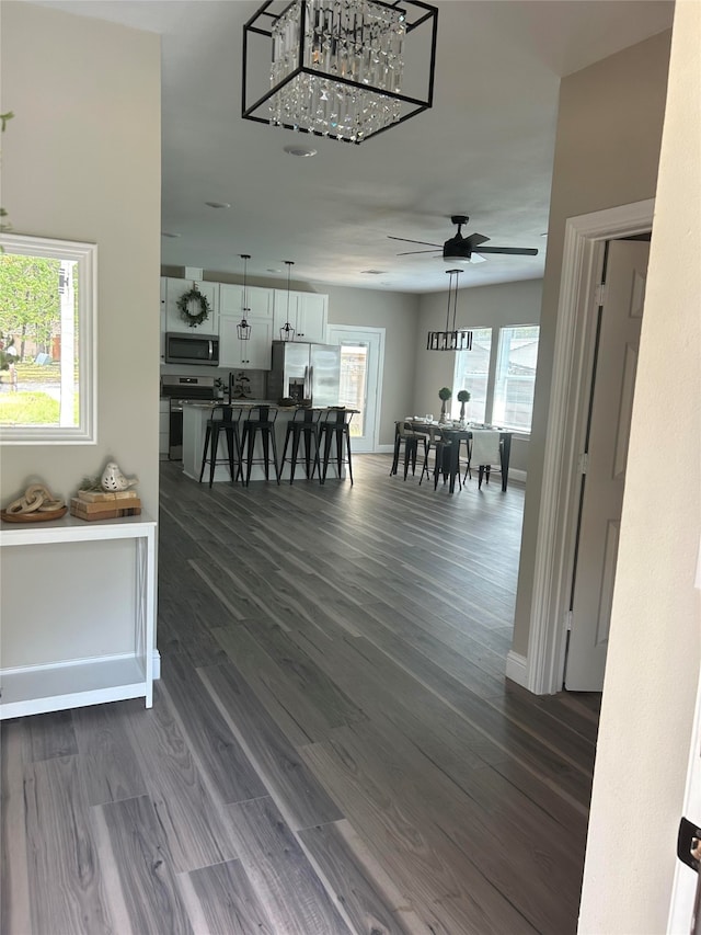 dining area with ceiling fan with notable chandelier, dark hardwood / wood-style floors, and a wealth of natural light