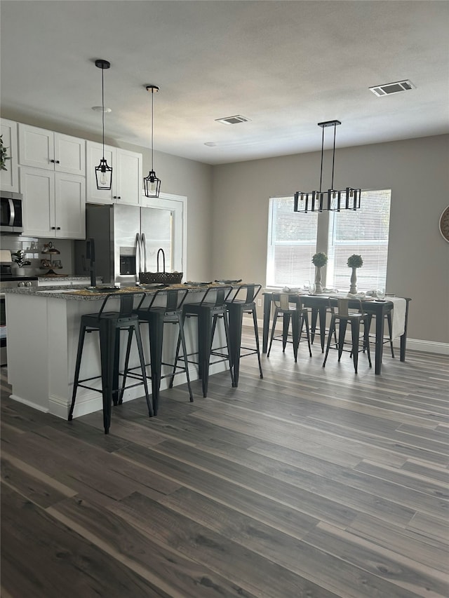 kitchen featuring dark stone counters, stainless steel appliances, white cabinetry, and dark hardwood / wood-style flooring