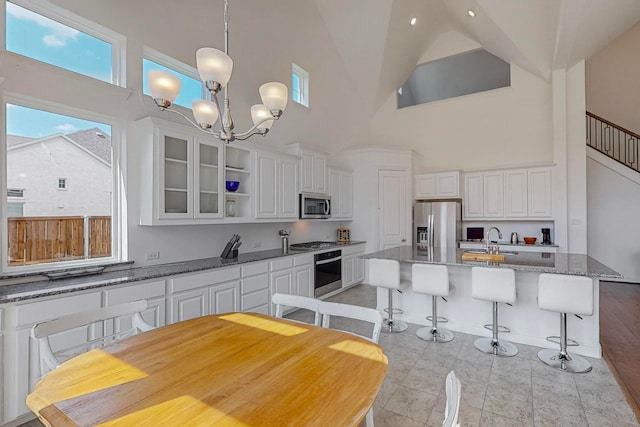 kitchen with high vaulted ceiling, stainless steel appliances, and white cabinetry