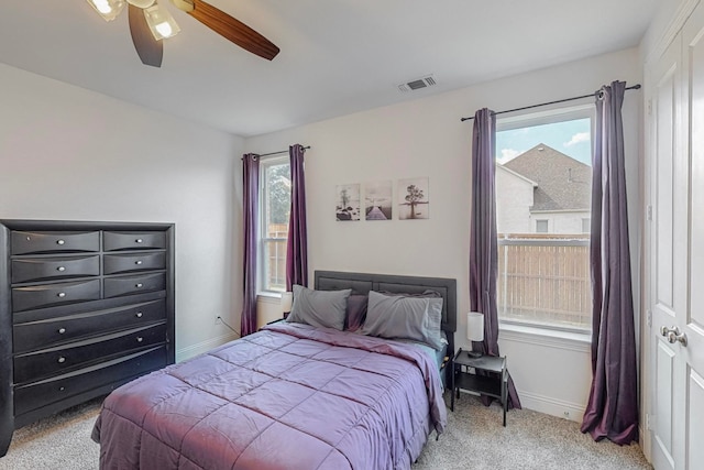 bedroom featuring multiple windows, light colored carpet, and ceiling fan