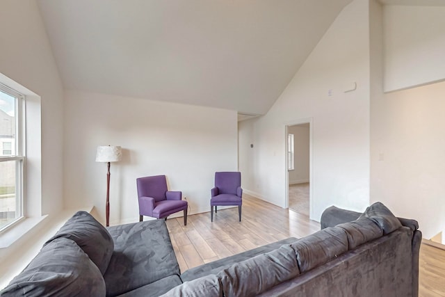 living room featuring plenty of natural light, high vaulted ceiling, and light hardwood / wood-style flooring