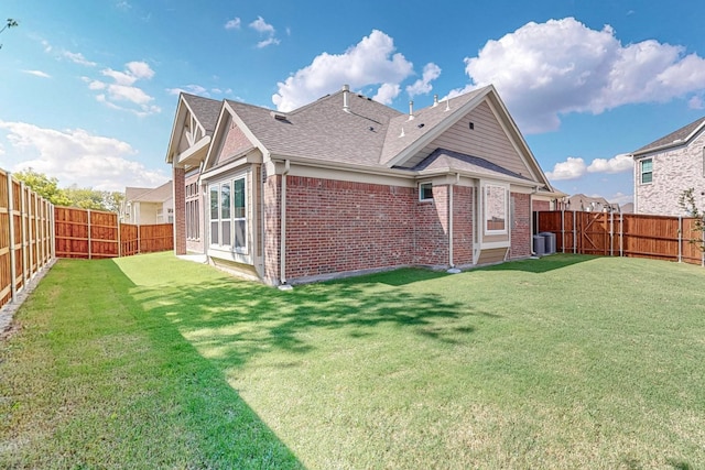 rear view of property with a lawn and central air condition unit