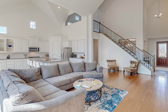 living room with light wood-type flooring, sink, and a high ceiling