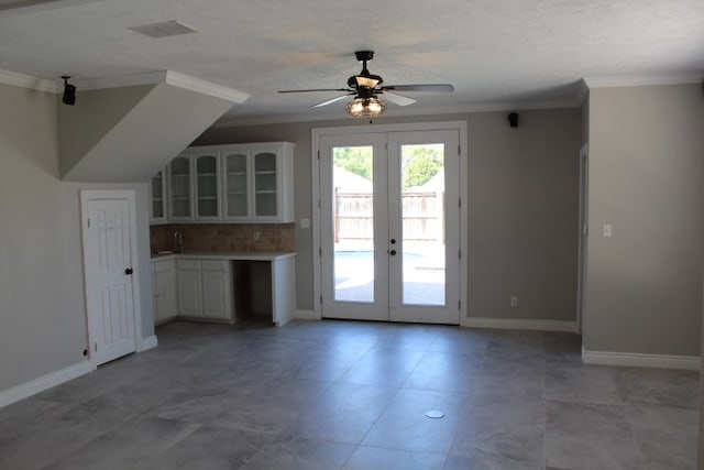 interior space featuring french doors, tasteful backsplash, ornamental molding, ceiling fan, and white cabinetry