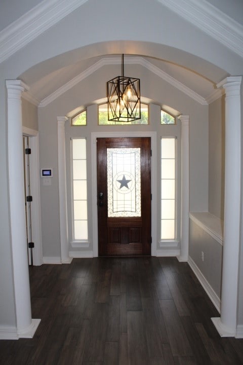 foyer featuring decorative columns, crown molding, a chandelier, and dark hardwood / wood-style floors