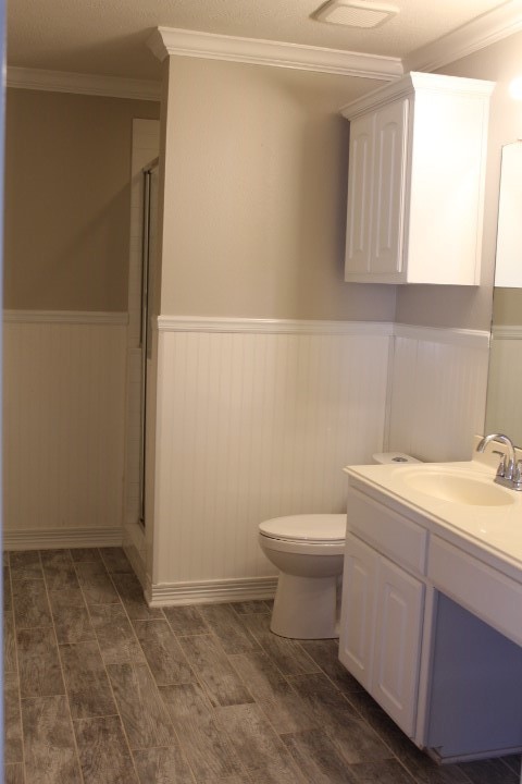 bathroom featuring ornamental molding, toilet, a shower with door, vanity, and hardwood / wood-style flooring