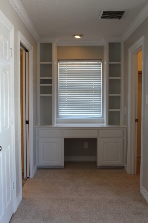 corridor featuring light colored carpet and ornamental molding