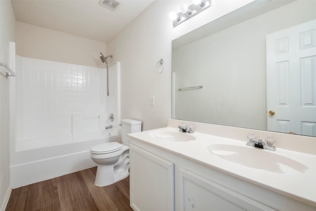 full bathroom featuring wood-type flooring, a textured ceiling, toilet, vanity, and shower / bathtub combination