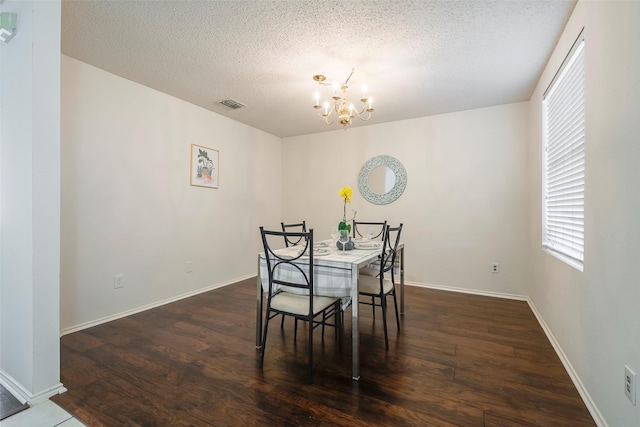 dining space with a textured ceiling, dark wood-type flooring, an inviting chandelier, and a healthy amount of sunlight