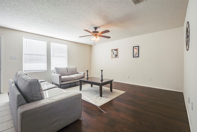 living room with a textured ceiling, dark hardwood / wood-style flooring, and ceiling fan