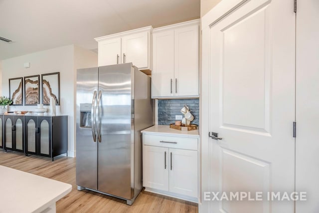 kitchen with stainless steel fridge, light hardwood / wood-style flooring, white cabinetry, and tasteful backsplash