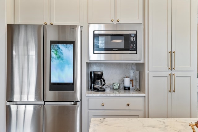 kitchen featuring light stone counters, appliances with stainless steel finishes, and white cabinetry