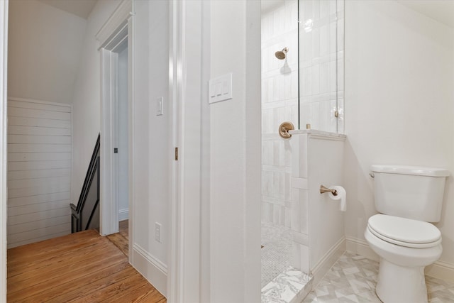 bathroom with hardwood / wood-style flooring, toilet, and tiled shower