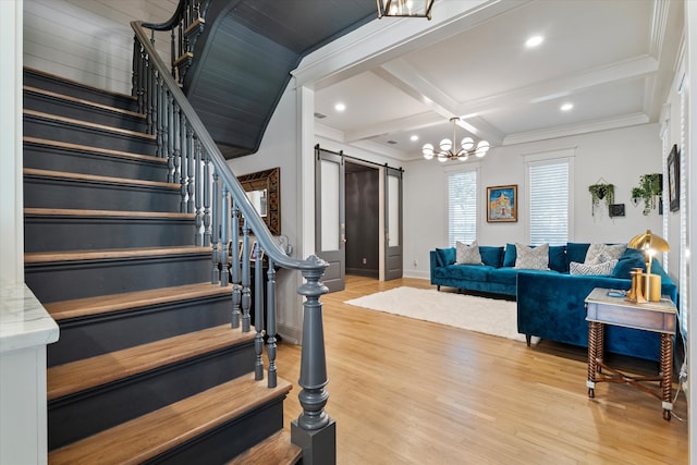 interior space with light hardwood / wood-style floors, beam ceiling, coffered ceiling, a barn door, and ornamental molding