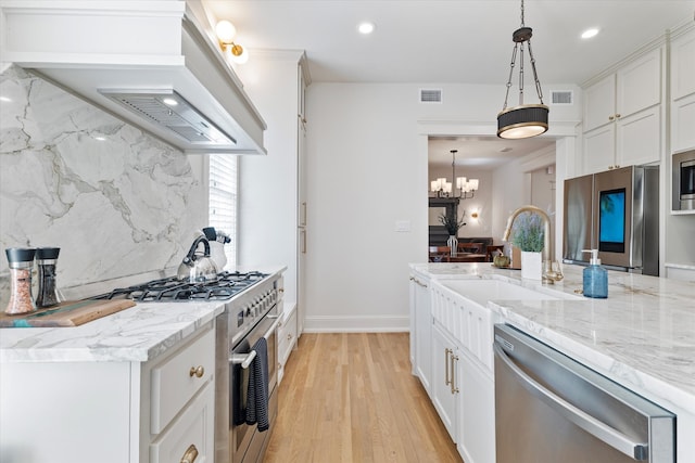 kitchen featuring white cabinets, decorative light fixtures, light hardwood / wood-style flooring, stainless steel appliances, and decorative backsplash