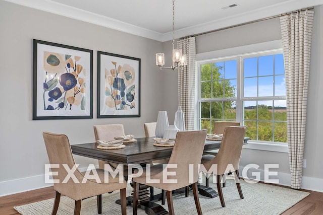 dining room featuring wood finished floors, visible vents, baseboards, ornamental molding, and an inviting chandelier