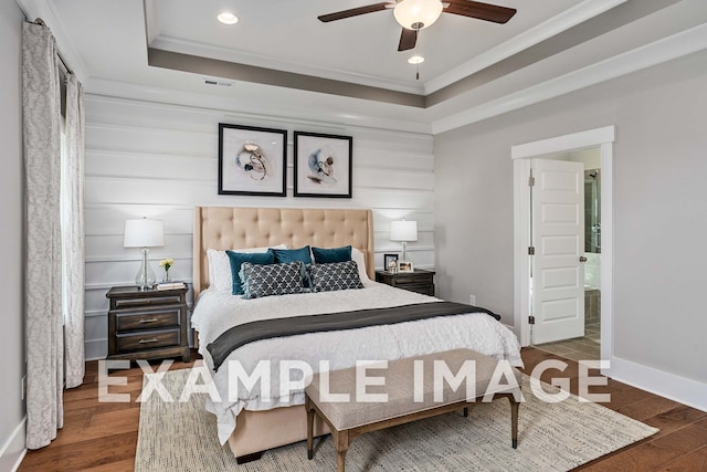 bedroom featuring connected bathroom, ceiling fan, crown molding, hardwood / wood-style floors, and a tray ceiling