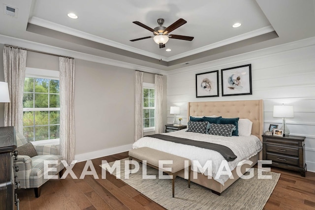 bedroom with dark wood-style floors, ornamental molding, and a raised ceiling