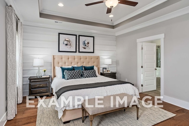 bedroom with ornamental molding, a raised ceiling, baseboards, and wood finished floors