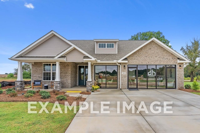 craftsman-style home with brick siding, a front lawn, a porch, and a shingled roof