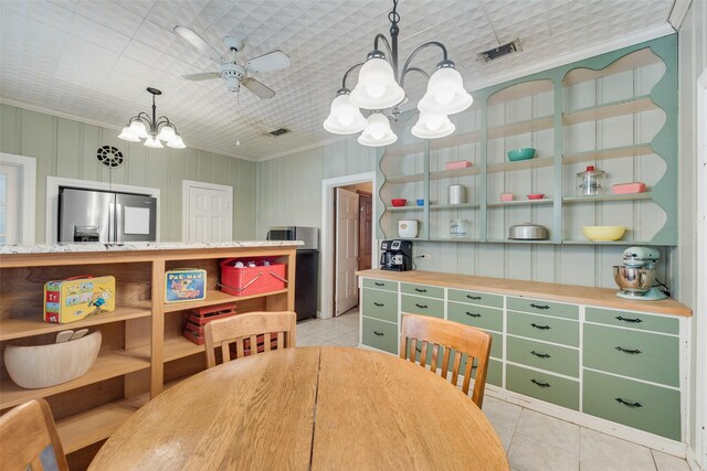 kitchen featuring hanging light fixtures, stainless steel appliances, ornamental molding, light stone counters, and ceiling fan with notable chandelier