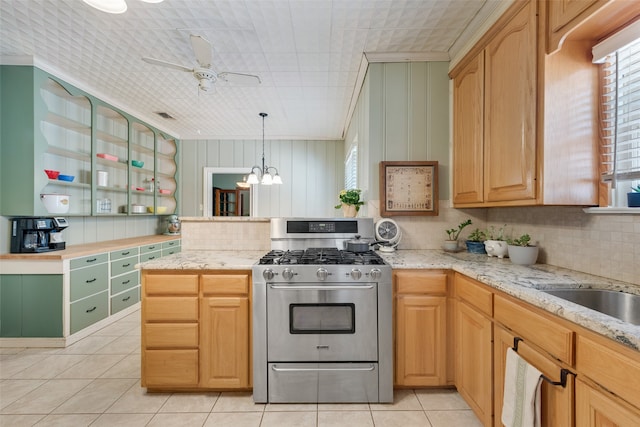 kitchen with light tile patterned floors, ceiling fan with notable chandelier, stainless steel range with gas stovetop, and decorative light fixtures