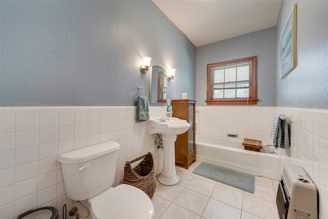 bathroom featuring toilet, tile walls, tile patterned floors, heating unit, and a washtub