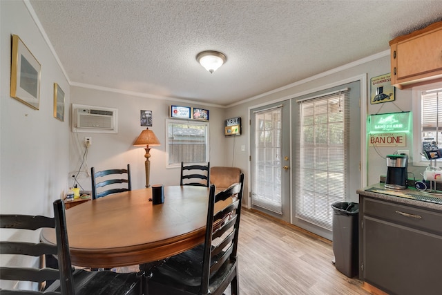 dining area featuring light wood-type flooring, crown molding, a textured ceiling, and a wall mounted air conditioner