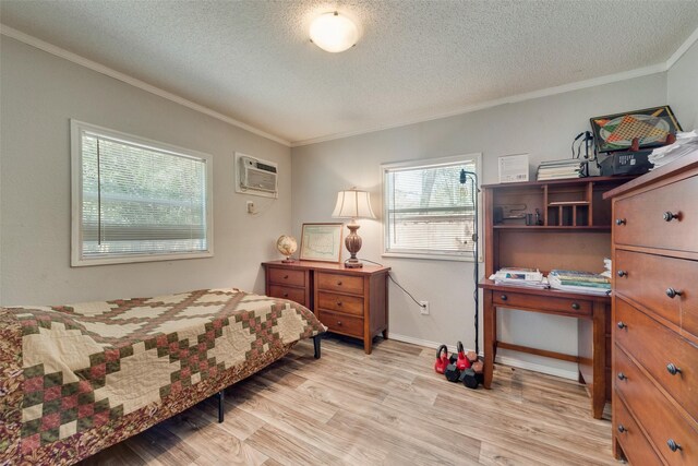 bedroom featuring light hardwood / wood-style floors, a wall unit AC, a textured ceiling, and ornamental molding