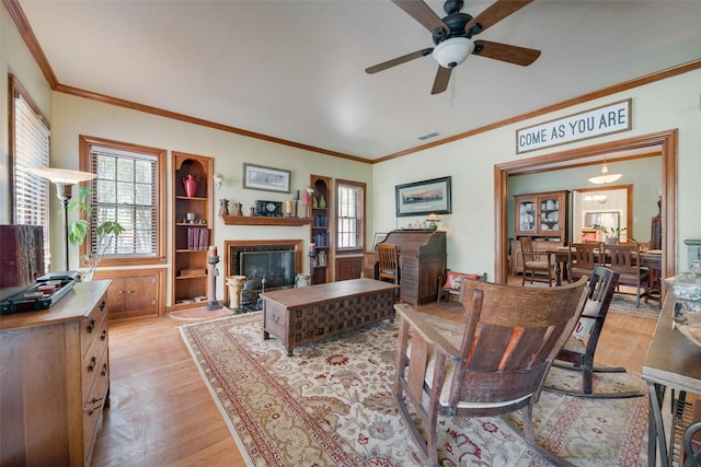 living room with ceiling fan, crown molding, and light wood-type flooring