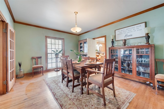 dining room featuring light wood-type flooring and crown molding