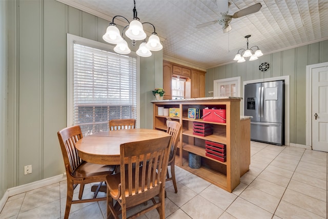 tiled dining area featuring ceiling fan with notable chandelier and crown molding