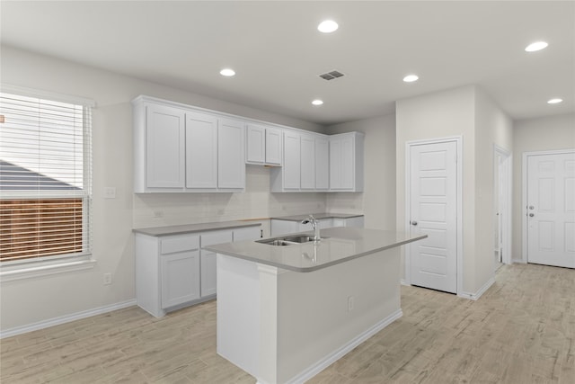 kitchen with an island with sink, white cabinets, and sink