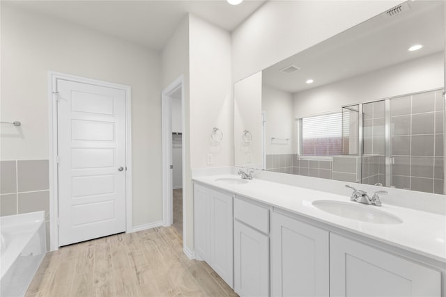 bathroom with hardwood / wood-style floors, vanity, and separate shower and tub