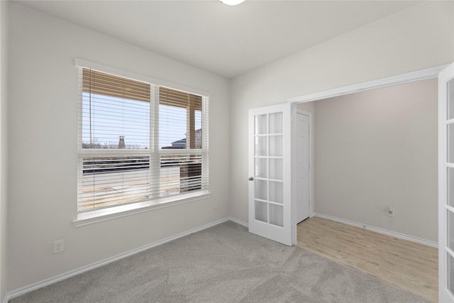 carpeted spare room featuring french doors