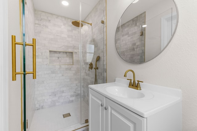 bathroom featuring a shower with door and vanity