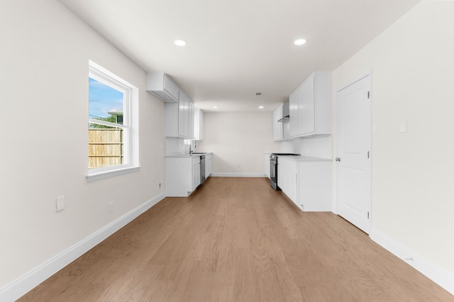 interior space with white cabinetry, light wood-type flooring, sink, and stainless steel range