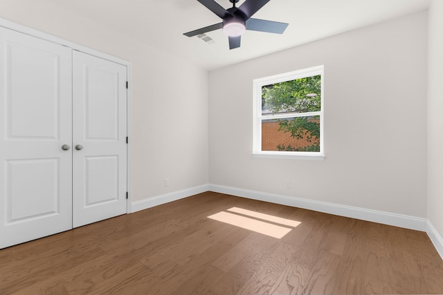 unfurnished bedroom featuring hardwood / wood-style flooring, ceiling fan, and a closet