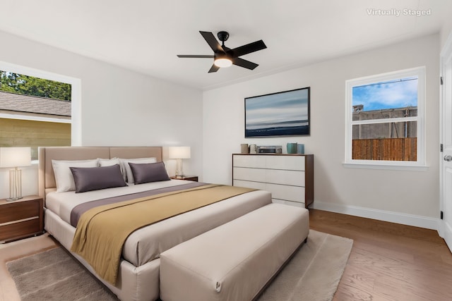 bedroom featuring ceiling fan, multiple windows, and light hardwood / wood-style floors