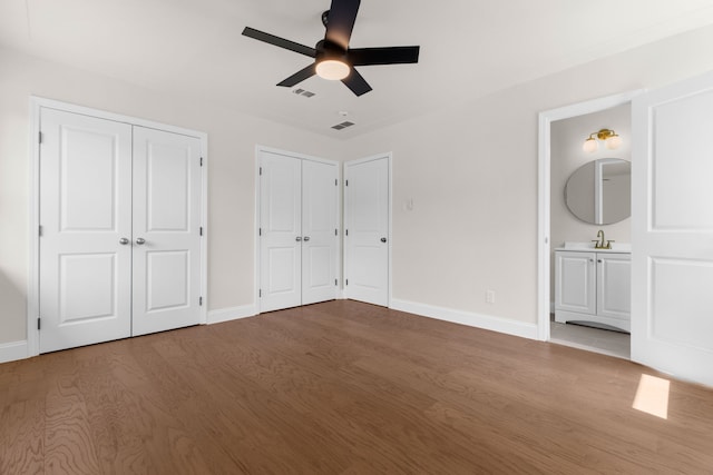 unfurnished bedroom with ensuite bathroom, light wood-type flooring, ceiling fan, and sink