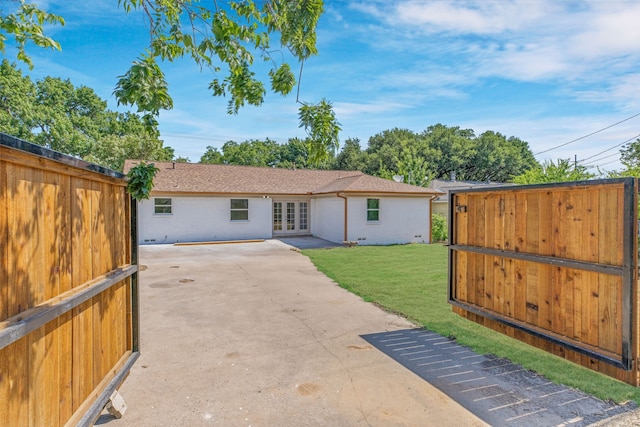 back of property with french doors, a patio, and a yard